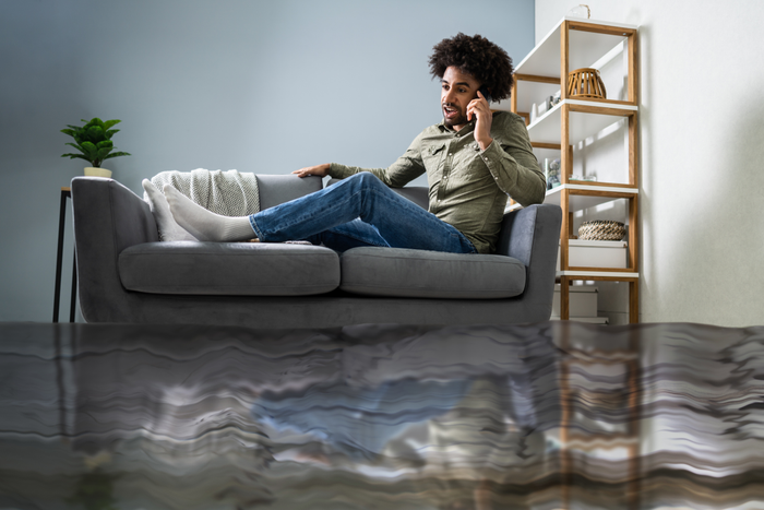Man Sitting On Sofa Calling To Plumber