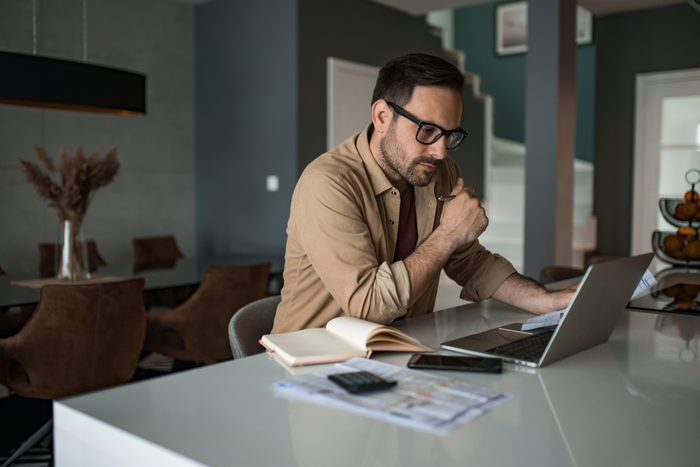 Young businessman working on laptop at home and paying bills and taxes.