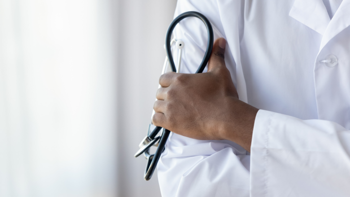 Male african doctor wear medical coat holding stethoscope, close up