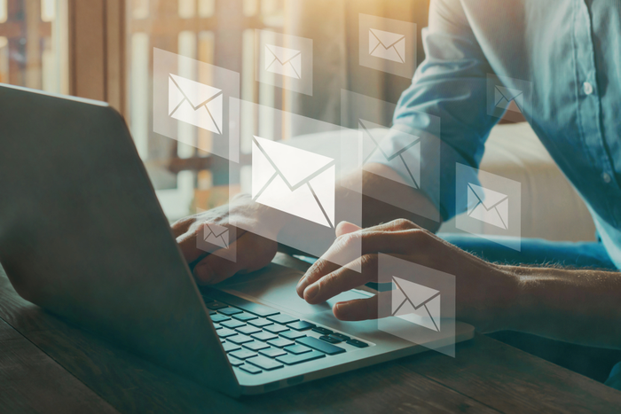 man in blue shirt using laptop, numerous translucent envelope signs floating around