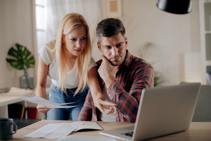 Worried young couple paying bills online in computer app stock photo