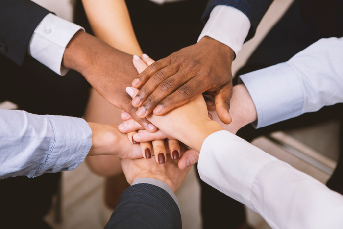 Multiethnic corporate teame stacking hands together in office