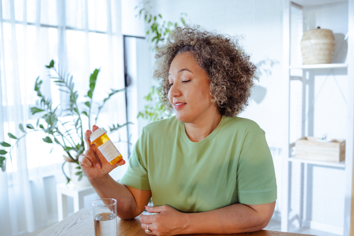 Mature woman holding a bottle of medicine in her hand