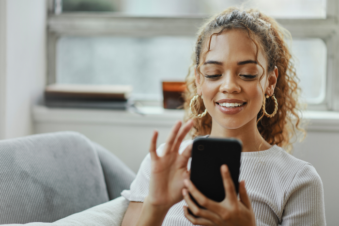 Black woman with smartphone on a sofa for networking online, mobile app or relax chat with home wifi. Young person on couch using phone for internet, social media post or email communication update