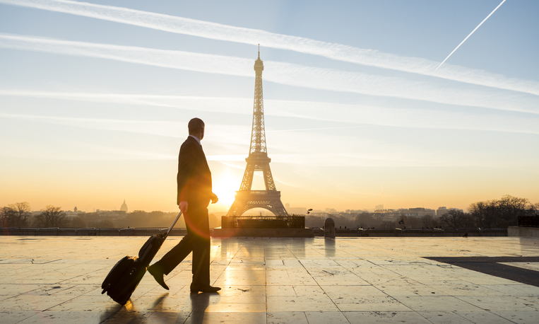 Travel businessman walking with suitcase at Eiffel Tower in Paris