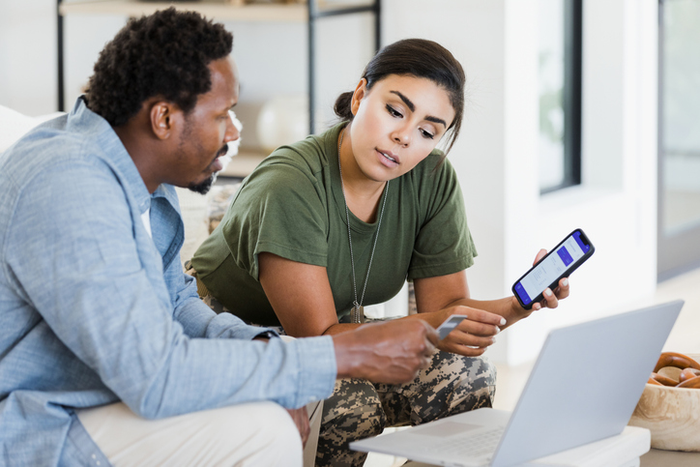Man and soldier wife discuss finances using phone and laptop