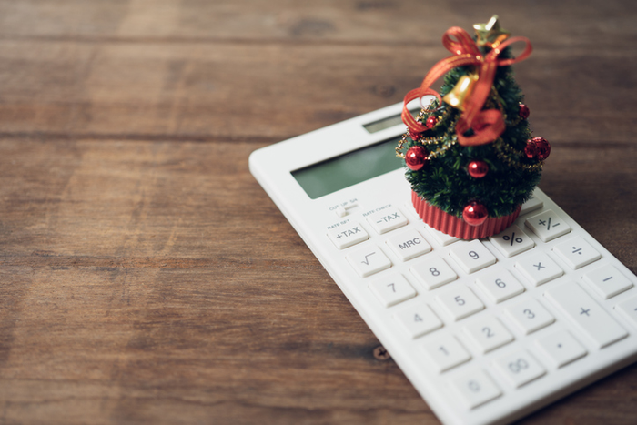 A beautifully decorated Christmas tree placed on a white calculator and with a miniature book. Christmas concept celebrated on December 25 every year.