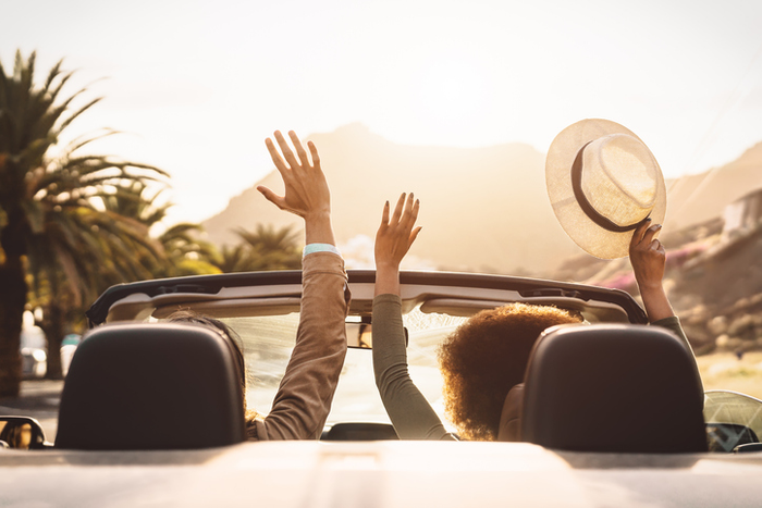 Happy young couple doing road trip in tropical city - Travel people having fun driving in trendy convertible car discovering new places - Relationship and youth vacation lifestyle concept