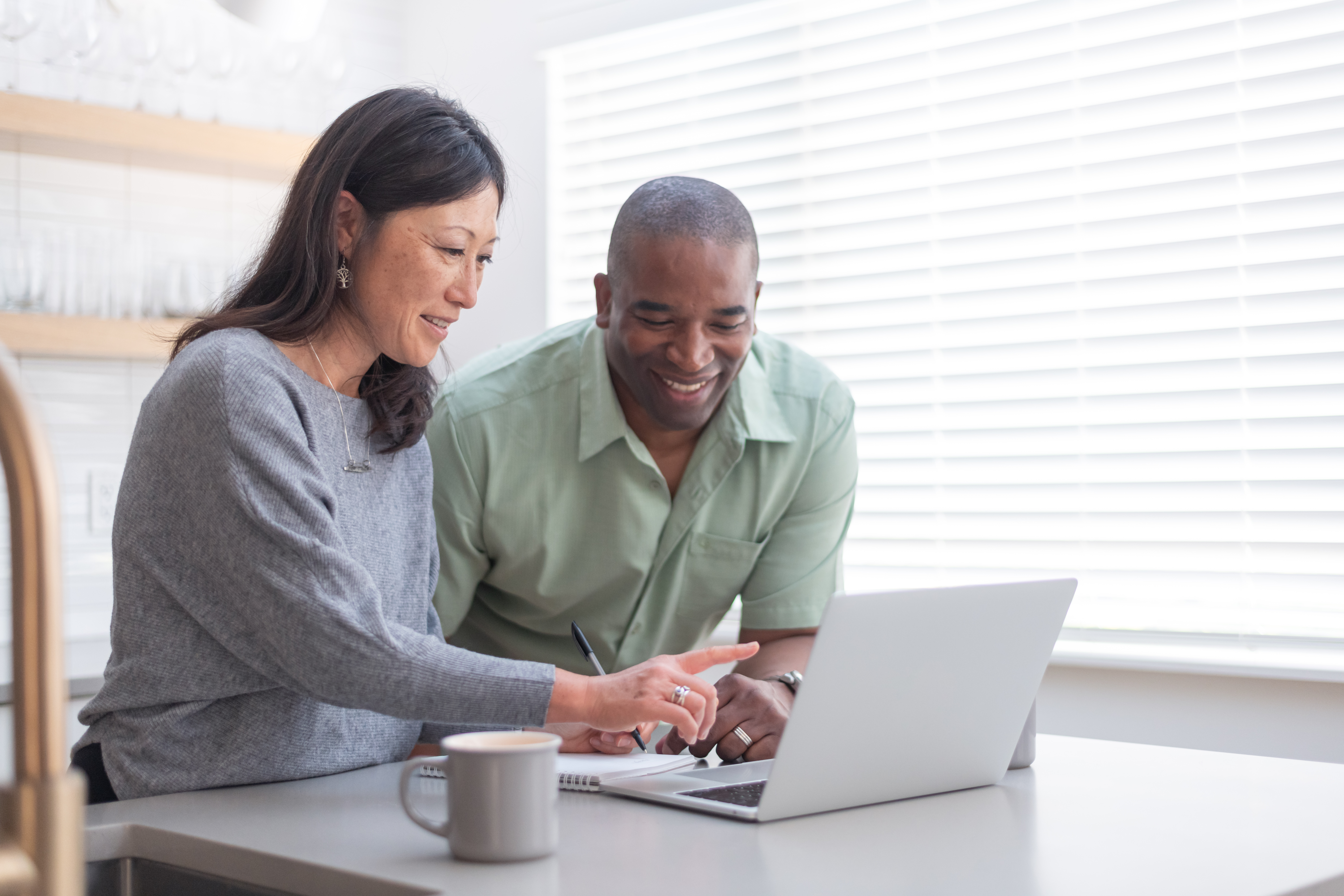 A couple use a laptop computer in their kitchen