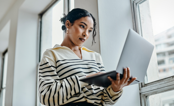 Black woman with laptop reading, typing and working for online digital newspaper, marketing or advertising company. Girl check email, post blog feedback or review social media content writing article