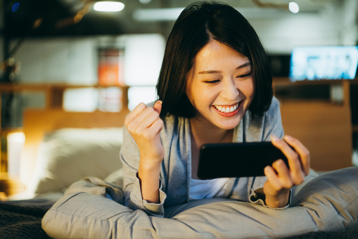 Happy girl on a bed uses a smartphone
