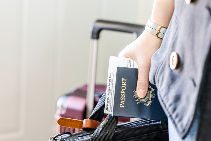 A person with US citizenship identification, vaccinated certified passport and personal belonging ready for travel in new normal.