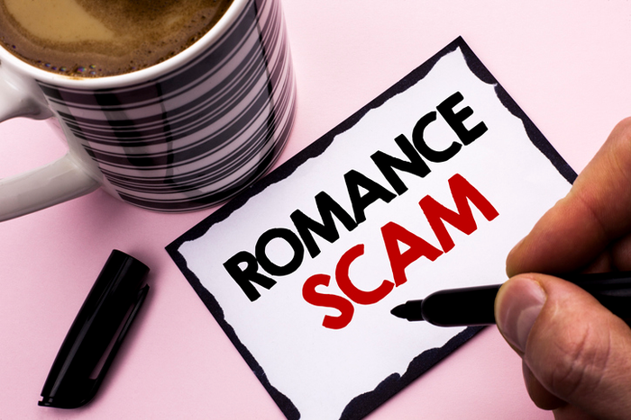 romance writers of canada scam Person writing "Romance Scam" on piece of paper next to a mug of coffee