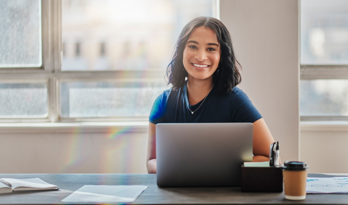 Business woman, smile and working on laptop in office or company looking happy and satisfied. Portrait of Brazilian female worker or employee typing email on computer and planning strategy for vision