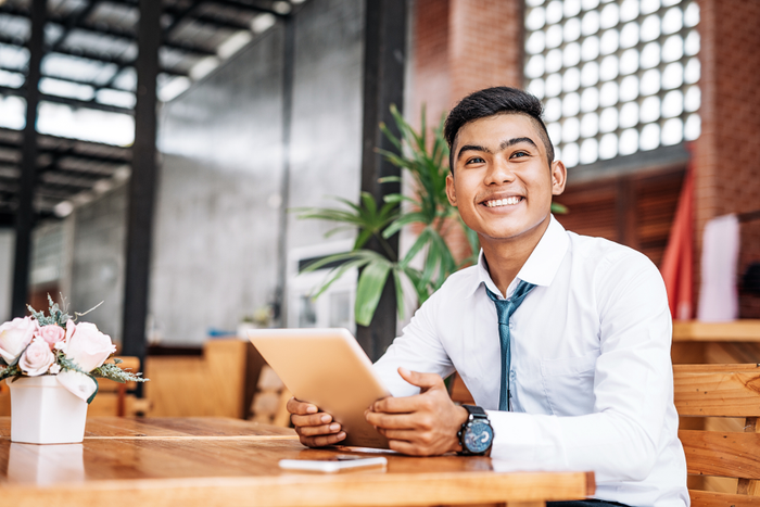 Cheerful Thai entrepreneur holding digital tablet