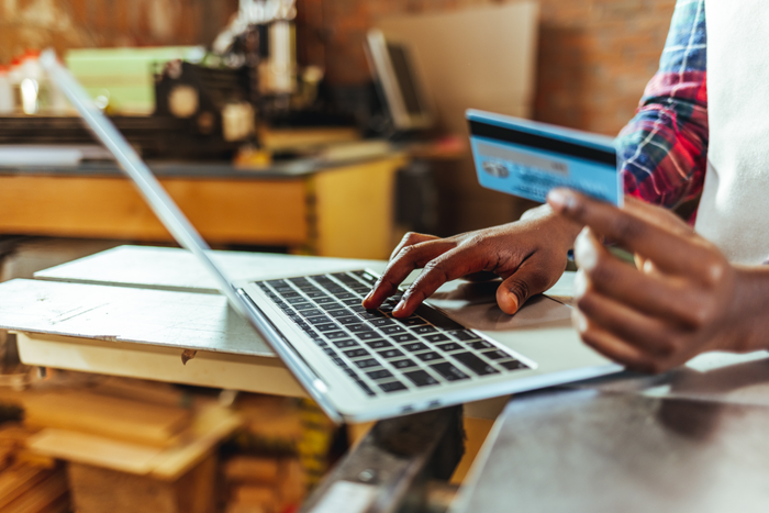 Carpenter at work shopping online using laptop computer and credit card