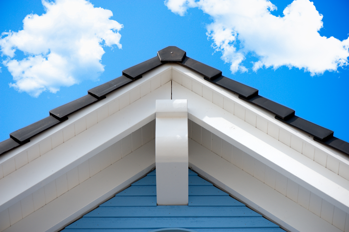 Detail of a house roof in front of a blue sky, with beautiful clouds