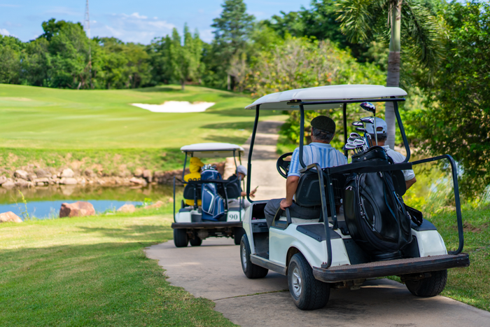 Group of Asian senior man driving golf cart on golf course in summer sunny day