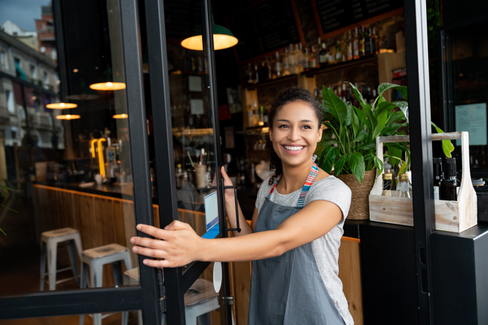 Happy business owner opening the door at a cafe