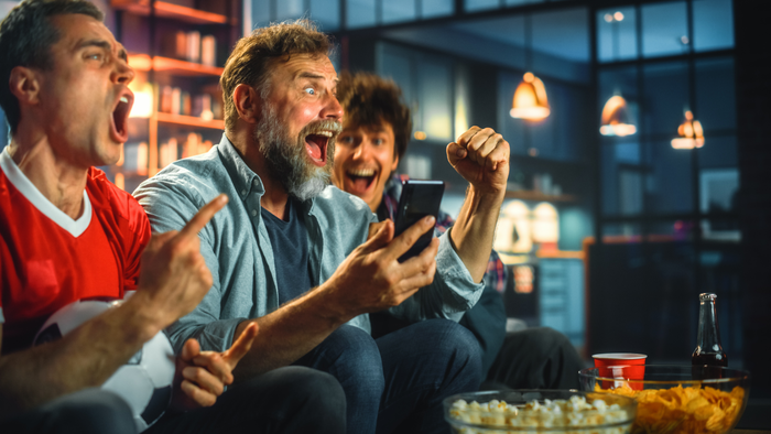 three men cheering watching a game