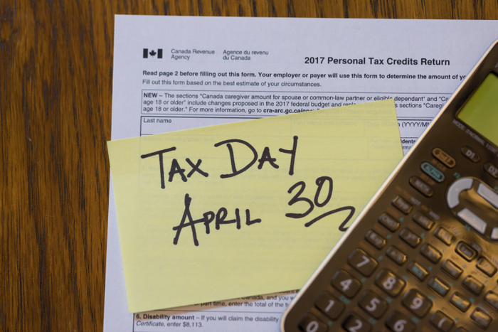 Tax Form and Calculator with Stick Note showing Canada Tax Day - April 30