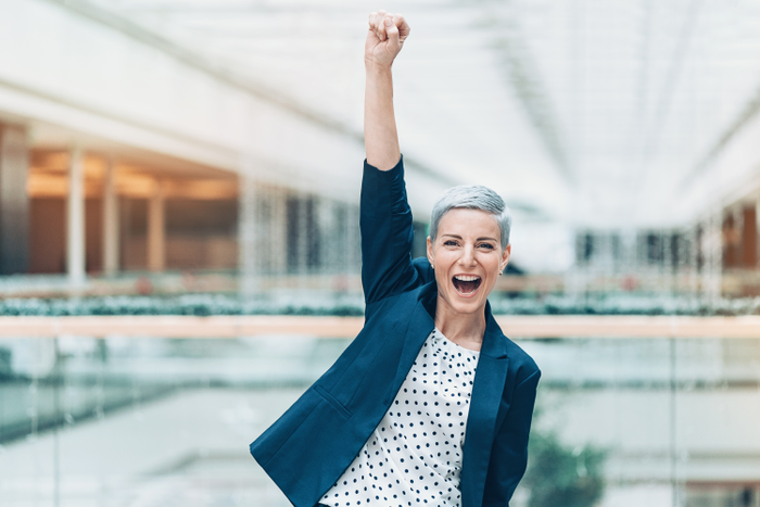 happy business owner pumping fist in the air in office