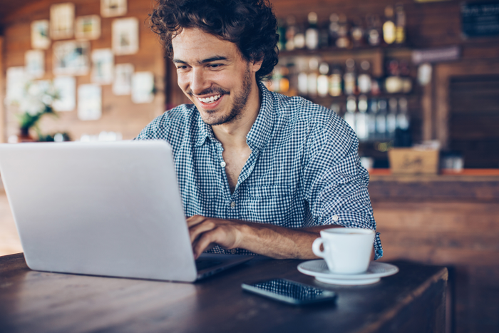 Young man working on a laptop in bistro, with copy space.