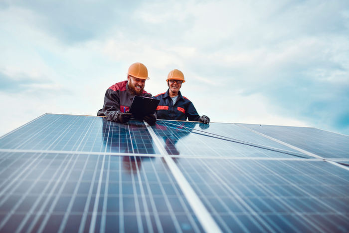 Senior Worker Helping Younger Male Measure Solar Panel Dimensions