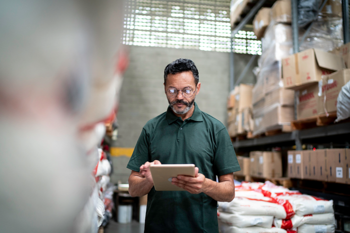 Manager using his tablet working in warehouse / industry