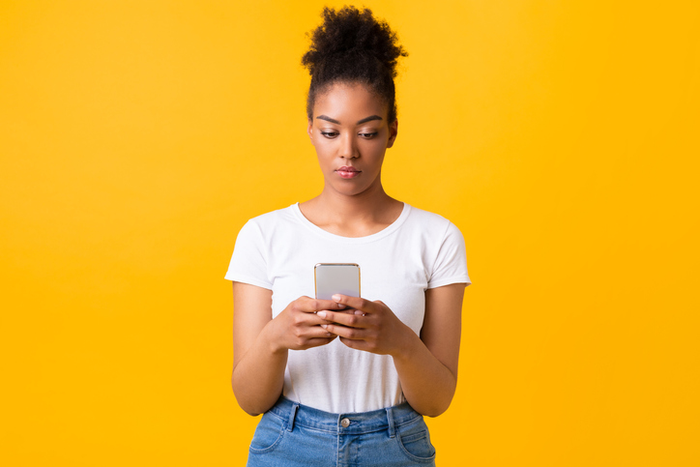 woman with cell phone in front of orange background
