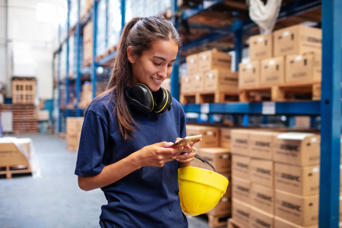 Woman warehouse worker using mobile phone