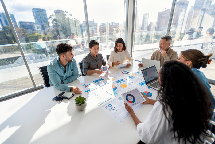 Multi racial group of people working with Paperwork on a board room table at a business presentation or seminar.