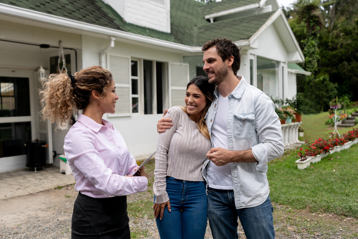 Portrait of a real estate agent showing a couple a beautiful house and looking very happy