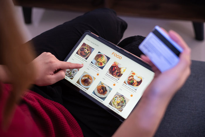 Close-up view of a woman ordering food online with credit card home