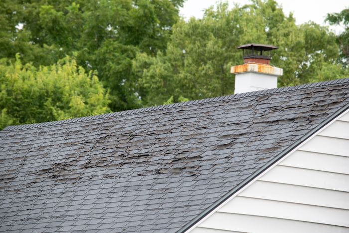 Damaged and old roofing shingles and gutter system on a house