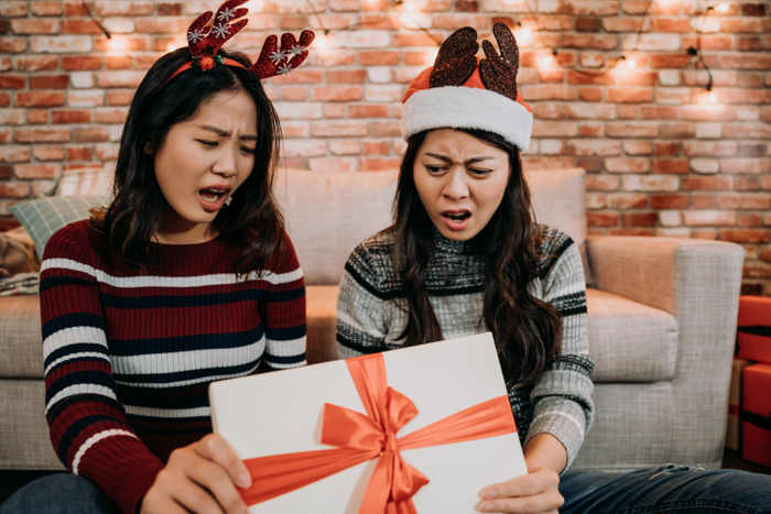 young girls open gift box day at home looking surprised and disappointed