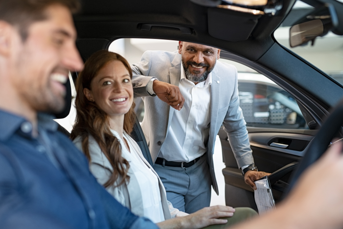 Salesman showing new car to couple