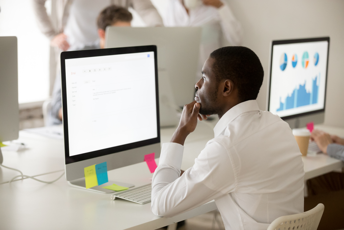 Serious african-american employee thinking over business email working on computer