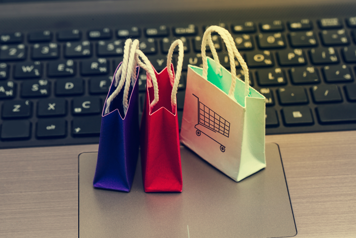 Online shopping concept; Three colorful paper shopping bags on notebook keyboard. E-commerce is the purchase of products and services on the internet can purchase goods or services foreign country.; Three colorful paper shopping bags on notebook keyboard.