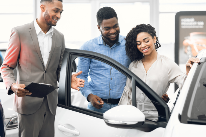 Car Selling Manager Showing Luxury Car To Buyers In Dealership