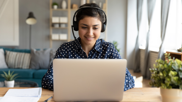 Smiling millennial ethnic female watch webinar on computer
