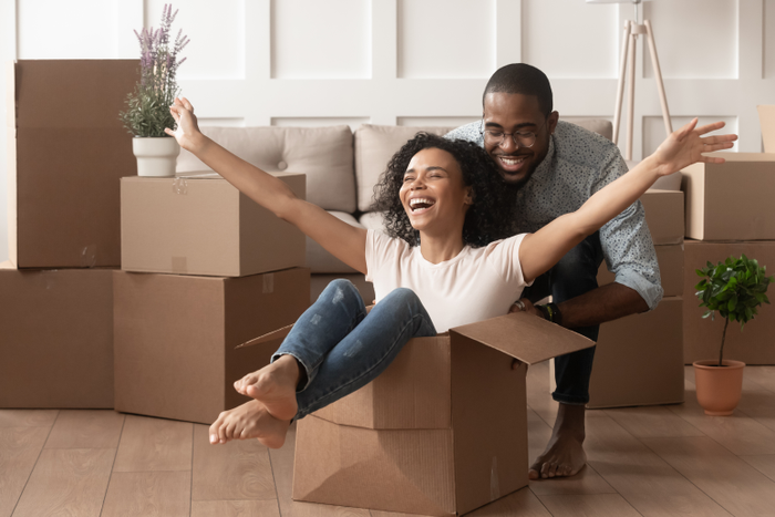 Happy african young couple riding in box on moving day