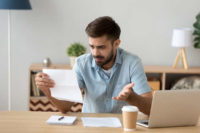 Confused frustrated man holding mail letter reading shocking unexpected news