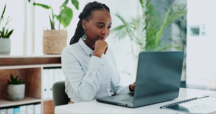 Business woman, thinking and laptop for online research in office and information on digital tech at desk. Black person, editor and inspiration on internet and creative writing on computer on blog