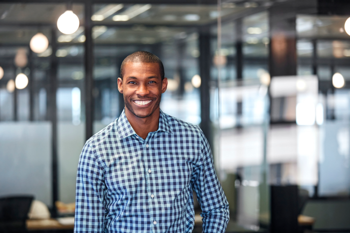 Portrait of smiling businessman against glass