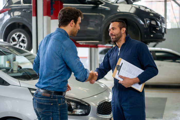 Man greeting a mechanic with a handshake at an auto repair shop