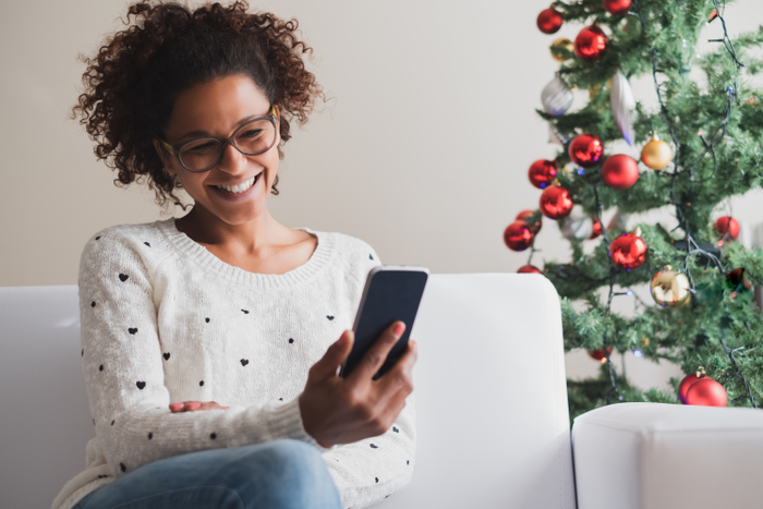 Cheerful woman holding mobile phone on christmas holiday