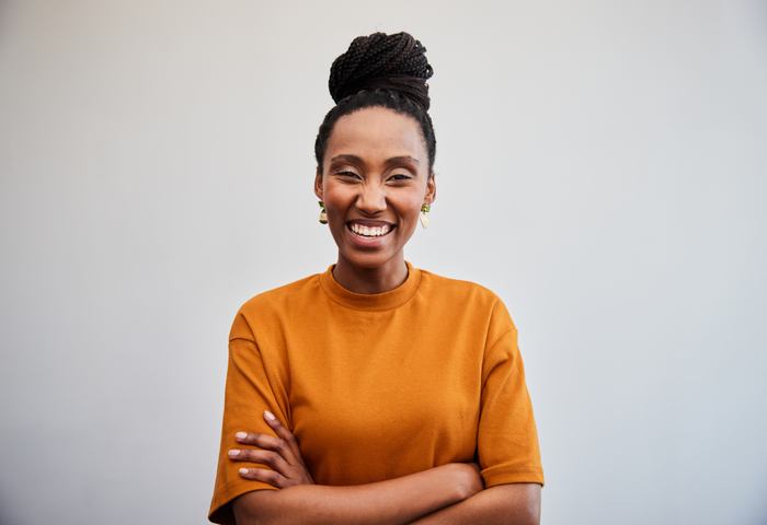 Young businesswoman laughing with her arms crossed against an office wall