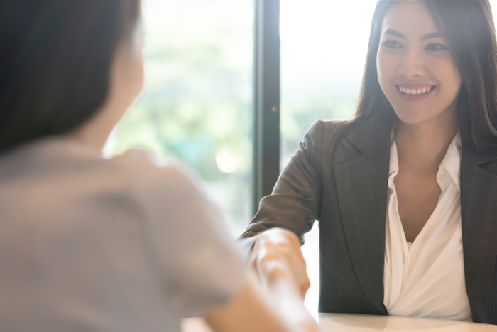 Portrait young Asian woman interviewer and interviewee shaking hands for a job interview .Business people handshake in modern office. Greeting deal concept