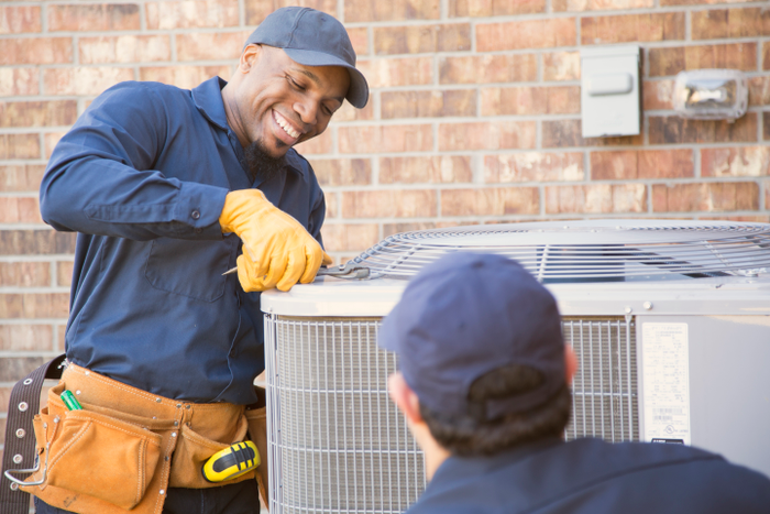 Multi-ethnic team of blue collar air conditioner repairmen at work.
